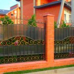 Красивый забор на кирпичных столбах с ковкой и поликарбонатом